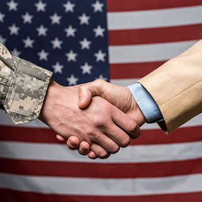 selective focus military men shaking hands near american flag